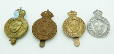 Four British Army Shropshire Yeomanry metal cap badges including a silver example marked TLM