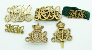 Six British Army Pay Corps metal badges including a Queen's Crown cap badge example