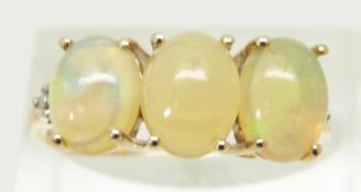 A 9ct gold ring set with three oval Ethiopian opal cabochons and diamonds, size R, 2.2g