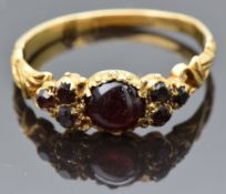 Victorian yellow metal ring set with a garnet cabochon flanked by further garnets, with pierced