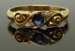 An 18ct gold ring set with a sapphire and two diamonds in a scrolling setting, size N/O, 2.31g