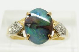 A 9ct gold ring set with an oval boulder opal cabochon of approximately 1.6cts and diamonds, 2.2g,