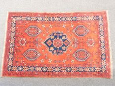 Turkoman rug with central navy blue gul and four other guls on a wine ground within a blue border,