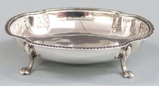 George V hallmarked silver trinket or bon bon dish with shaped edge, raised on four paw feet,