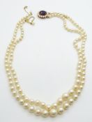 A double strand of cultured pearls with a 9ct gold clasp set with an amethyst and pearls