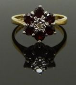 An 18ct gold ring set with a diamond surrounded by garnets, size K, 3.39g
