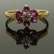 A 9ct gold ring set with rubies and a diamond with textured shoulders, size N, 2.13g