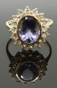 A 9ct gold ring set with an oval cut amethyst surrounded by white sapphires, size M, 3.71g