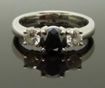 An 18ct white gold ring set with a black diamond flanked by two diamonds, each approximately 0.