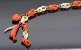 Victorian stick pin made up of alternating coral links, with three charms including heart and mother