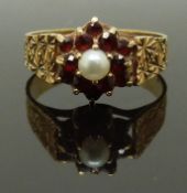 A 9ct gold ring set with a pearl surrounded by garnets with textured shoulders, size K, 2.34g