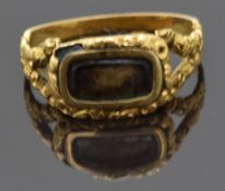 Victorian mourning ring with a central glass compartment and floral decoration to the border and