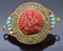 A 19thC Indian yellow metal pendant/buckle set with a carved coral section depicting Ganesh