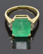 An 18ct gold ring set with a natural emerald cut emerald of approximately 5.97ct and three