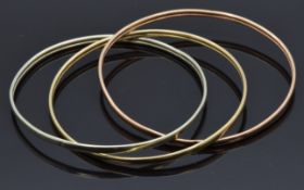 A 9ct gold tri-coloured bangle made up of three linked bangles, 9.4g