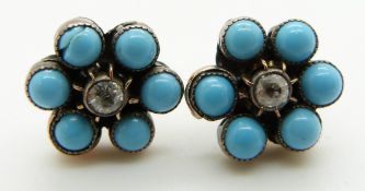 A pair of earrings set with a diamond to each surrounded by faux turquoise