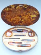 George V ladies faux tortoiseshell dressing set in fitted oval case set with silver gilt hinges,