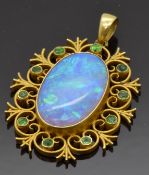 An early 20thC 15ct gold pendant set with a black opal within a scrolling border set with
