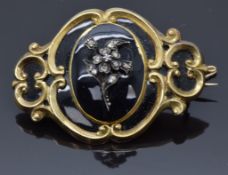 Victorian mourning brooch set with black enamel inside a scrolling border and diamonds in the form