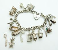 A silver charm bracelet with 11 charms including a spider, train, stork, etc