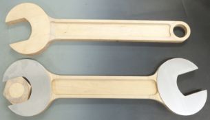 Large novelty wood and aluminium spanner with nut in jaws together with another novelty wooden