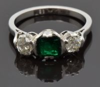 An 18ct white gold ring set with an emerald cut emerald of approximately 0.8ct and two diamonds,