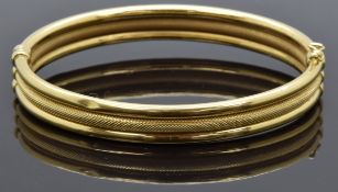 An 18ct gold bangle made up of three bands, one with a textured finish, 14.7g