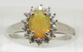 A 9ct white gold ring set with an oval Indonesian opal surrounded by white sapphires, 2g, size N