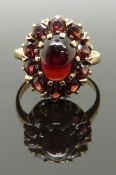 A 9ct gold ring with an opal cabochon surrounded by further garnets, size K, 3.89g