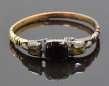 Georgian ring set with a foiled garnet flanked by two diamonds, with scrolling detail to the
