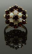 A 9ct gold ring set with opals and garnets in a large cluster, size I, 4.68g