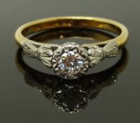 An 18ct gold ring set with a round cut diamond in a platinum setting with bow detail to the