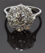 A platinum ring set with a round cut diamond of approximately 1.3ct surrounded by eight further