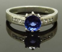 An 18ct white gold ring set with a round cut tanzanite and diamonds to the shoulders, with