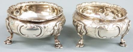 Pair of Victorian hallmarked silver salts with embossed decoration and raised on three feet,