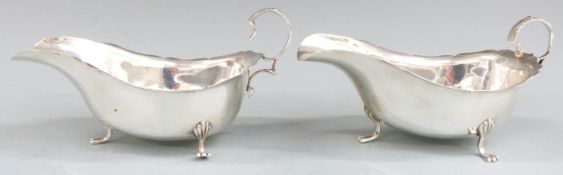 Pair of  George V hallmarked silver sauce boats with shaped edges raised on three feet, Birmingham