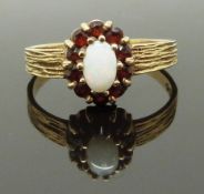 A 9ct gold ring with an opal surrounded by garnets, size M, 2.08g