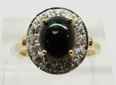 A 9ct gold ring set with an oval Mezezo opal cabochon and zircon, 3.1g, size N