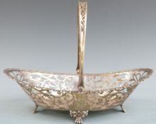George V hallmarked silver swing handled basket with pierced decoration, raised on four paw feet,