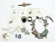 A silver charm bracelet with enamel charms, two silver rings, etc