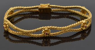 An 18ct gold bracelet made up of textured links and flower sections set with rubies, 23g
