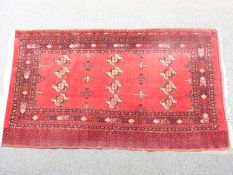 Turkoman rug with twelve central guls on deep red ground,surrounded by border filled with koc