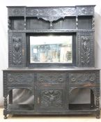 Carved oak dresser, the top being cupboards flanking a bevelled edge mirror, the base with fitted