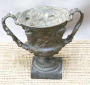 Spelter miniature twin handled vase or urn with mask and foliate decoration, on square slate or