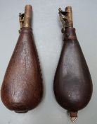 Two leather and brass shot flasks each with suspension loops, largest 22.5cm long.