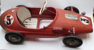 Tri-ang pressed steel pedal racing car with red body, rubber tyres and racing number 3, 118cm long.