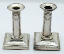 Victorian pair of hallmarked silver candlesticks with embossed swag decoration, London 1895 and 1897