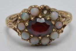A 9ct gold ring set with a garnet and opals, in antique Cardiff ring box