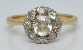 An 18ct gold ring set with an old cut diamond of approximately 0.4ct surrounded by further diamonds,