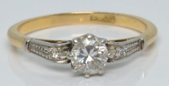 An 18ct gold ring set with a diamond of approximately 0.2ct and a further diamond to each